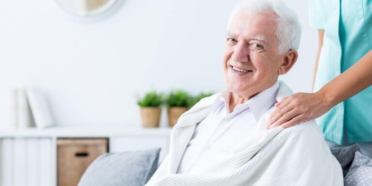 Elderly Man Smiling as Nurse Offers Care at Independent Living Facility