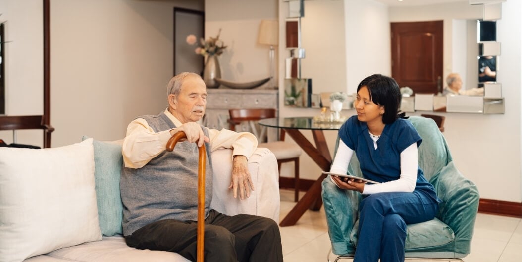 Female Nurse Consulting with Elderly Male Resident Using a Tablet at an Independent Living Facility
