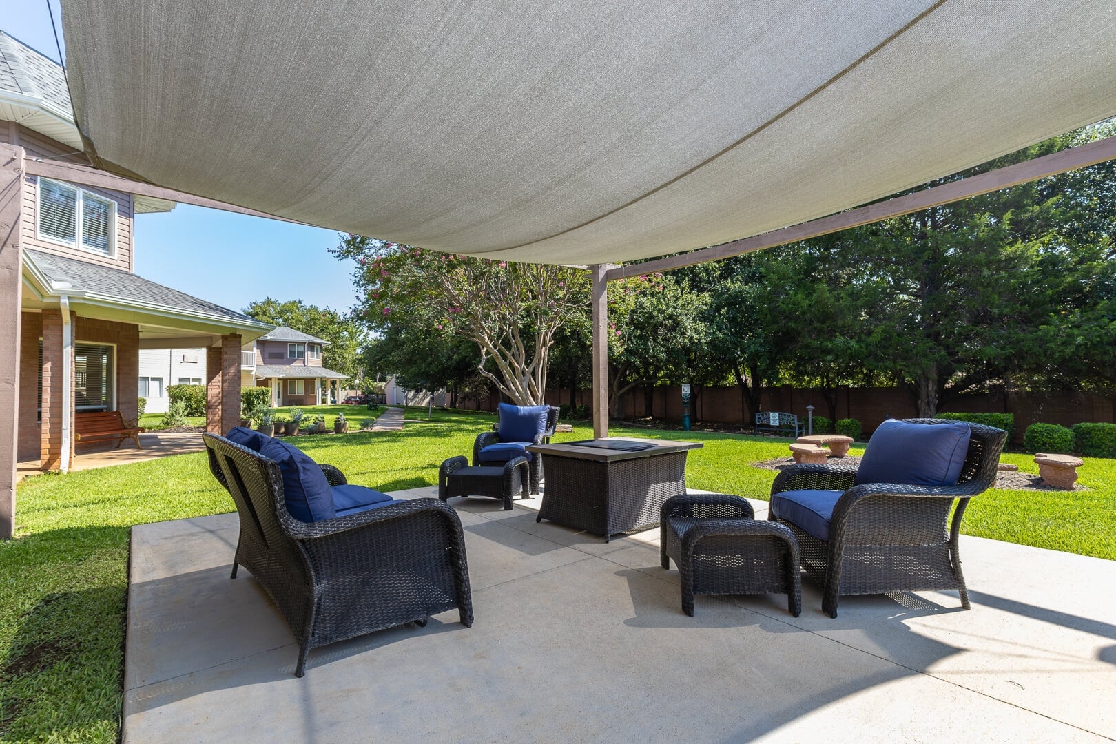 Shaded Outdoor Patio with Wicker Seating and Fire Pit at Our Independent Living Facility