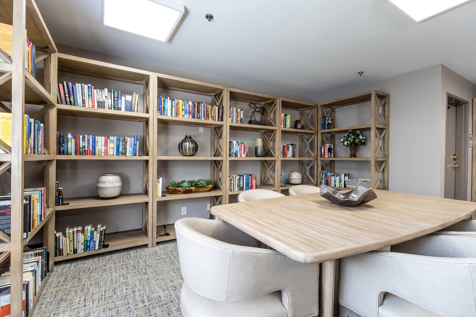 Bright Library Nook with Tall Bookshelves and Reading Table in Our Independent Living Community