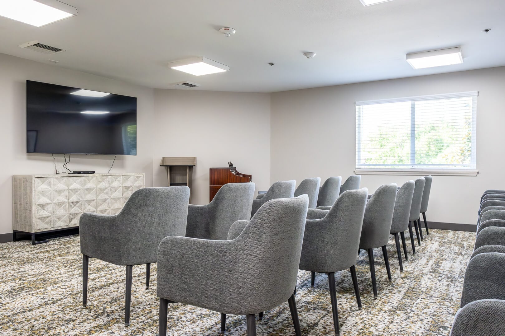 Theater Style Activity Room with Cushioned Chairs and Television in Independent Living