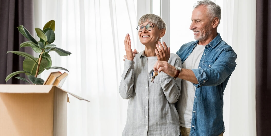 Smiling Elderly Couple Holding New Keys at Independent Facility